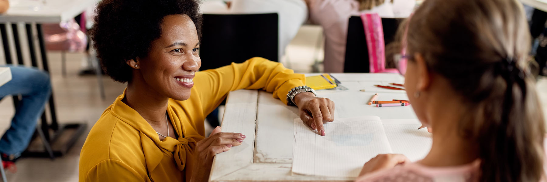 A teacher smiling at her student while assisting her